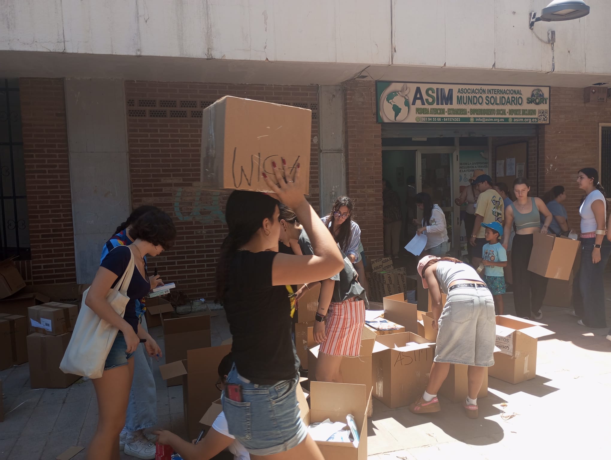Voluntarios clasificando cajas de donativos frente a la fachada de ASIM